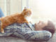 Young man with fluffy cat lying on a carpet